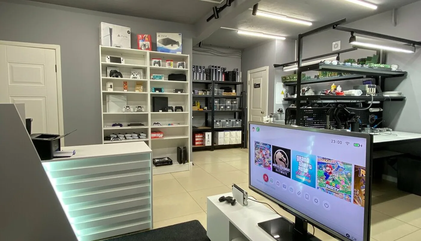 Зал сервиса TopConsole: стойка приёма, витрина с приставками и рабочая зона мастера